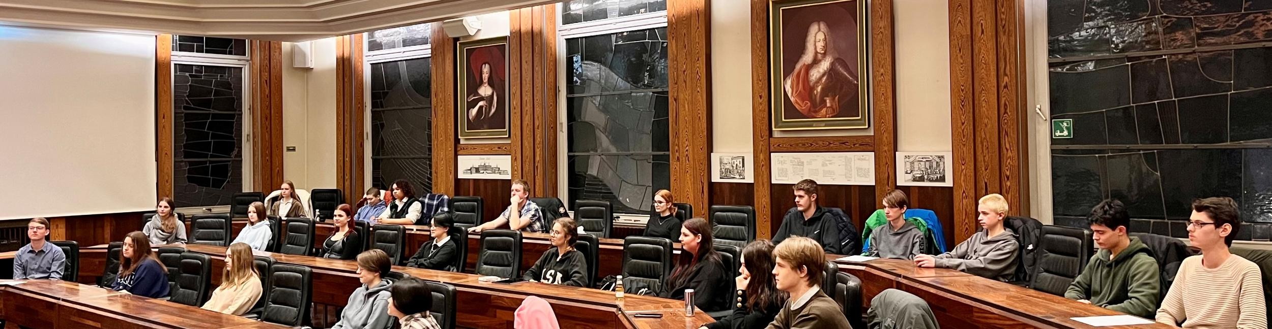 Several young people sit in a meeting room 