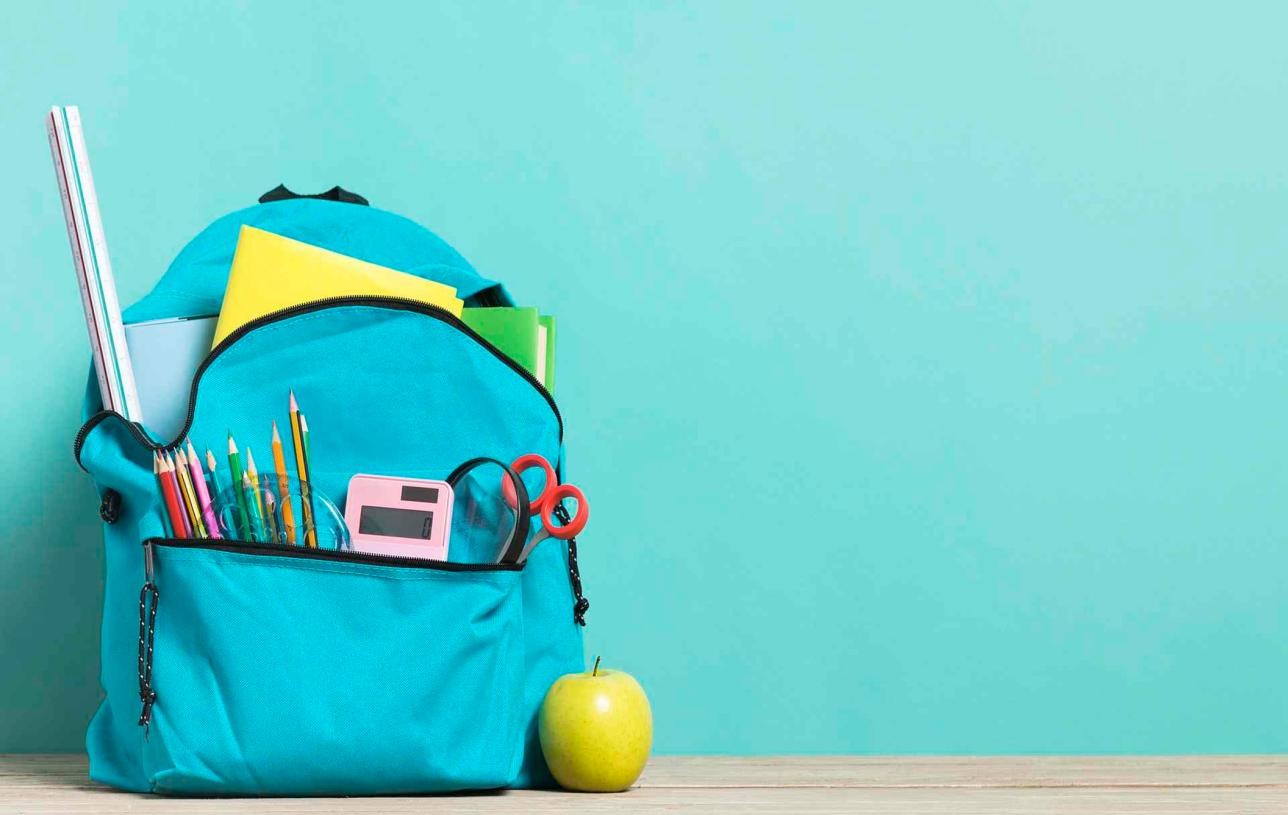 Blue school backpack lying in front of a wall