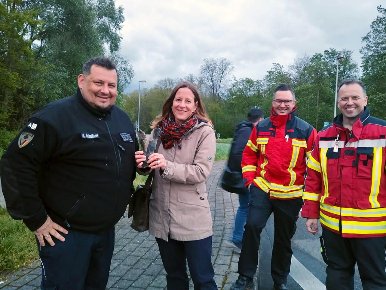 Gruppenfoto OB Müller mit einem Splitter der gesprengten Weltkriegsbombe in der Hand und Einsatzkräfte