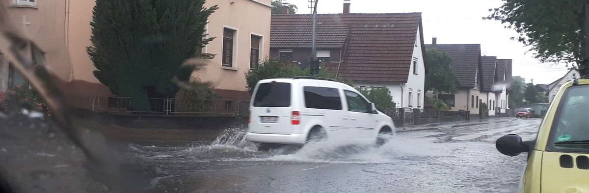 Une route inondée, une voiture qui essaie de passer