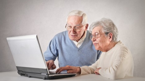 Two senior citizens in front of a laptop