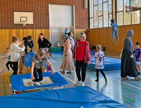 Kinder turnen in einer Sporthalle, Eltern sind mit dabei