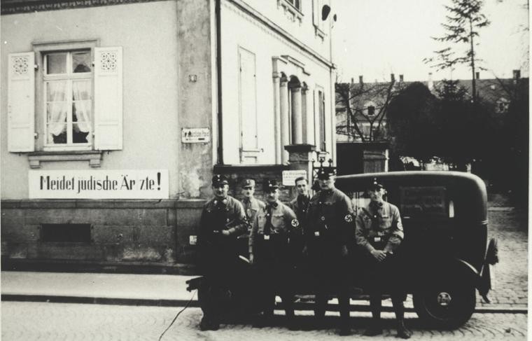 SA members stand in front of a car in front of the practice of the doctor Alfred Grünebaum