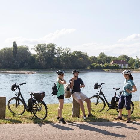 Cyclists take a break on the banks of the Rhine in Plittersdorf