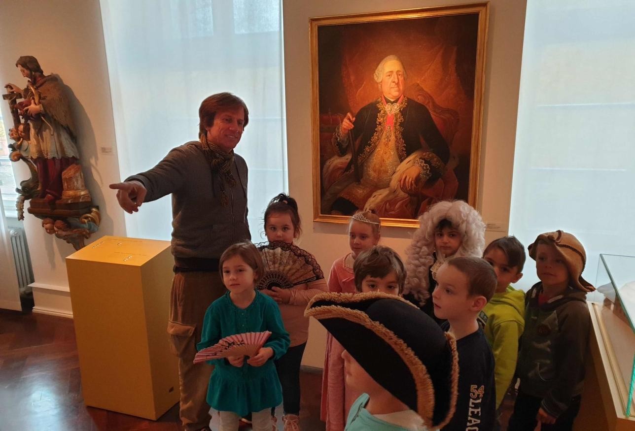 Museum educator Eric Schütt surrounded by children in the Rastatt City Museum.