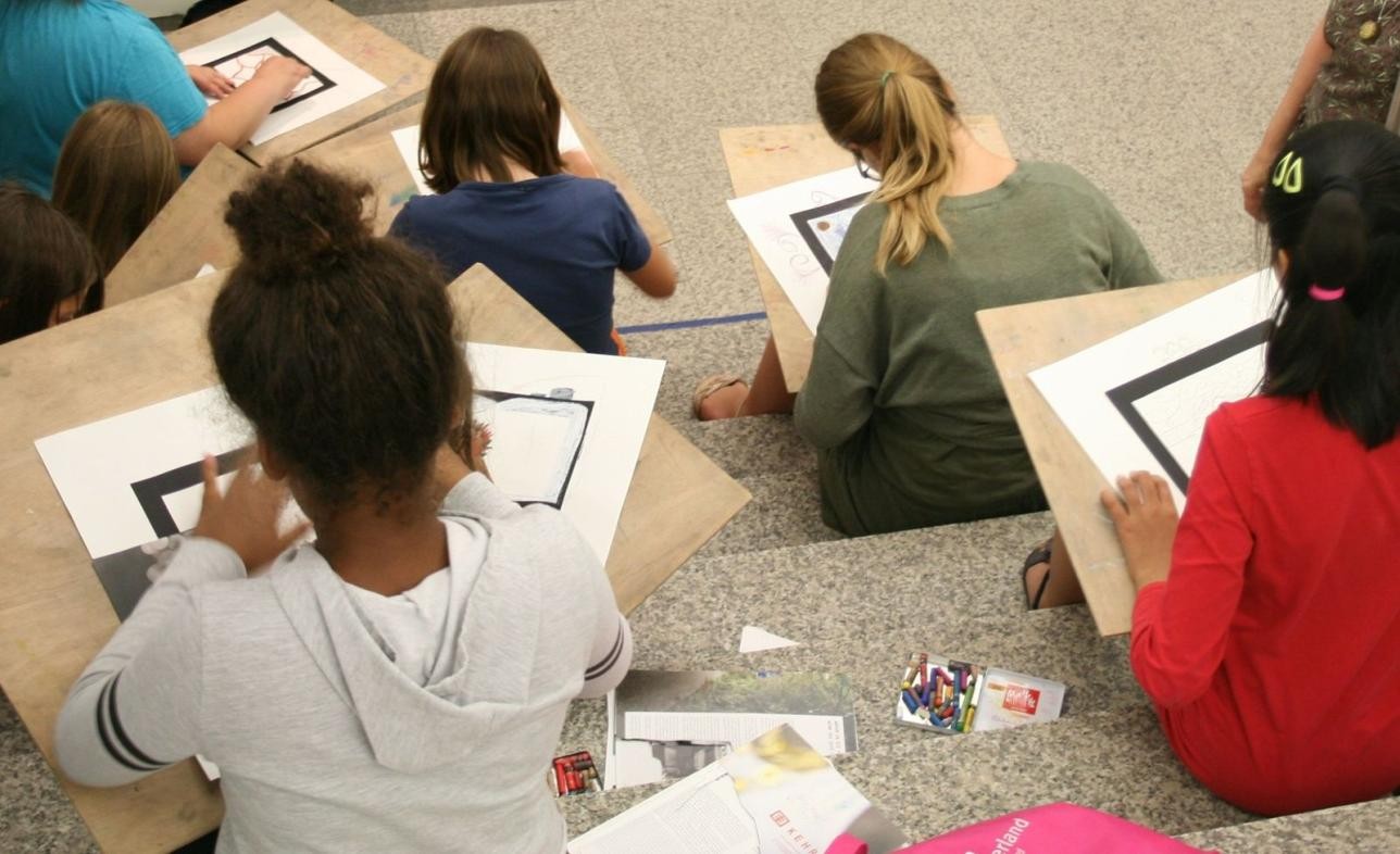 Mehrere Kinder sitzen auf einer Treppe und zeichnen Bilder.