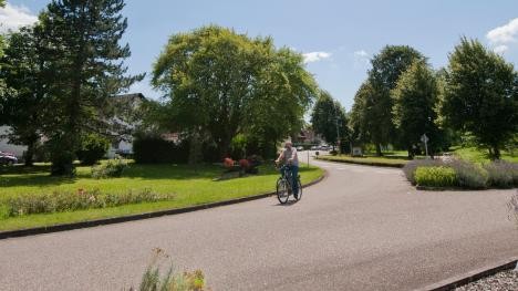 Bicyclist on the road at the entrance to the village of Wintersdorf