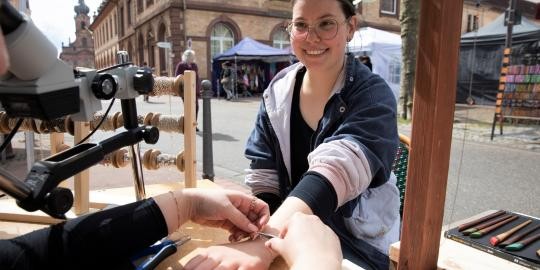 Frau probiert ein Armband am Stand beim Kunsthandwerkermarkt in Rastatt an.
