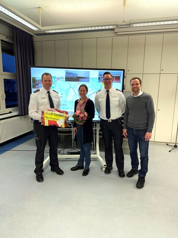 Mayor Monika Müller with a bouquet of flowers surrounded by firefighters and Mayor Raphael Knoth