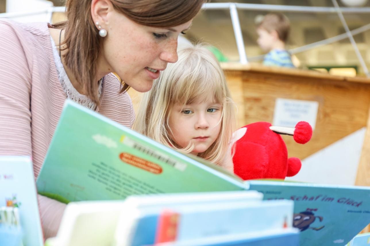 Frau liest einem Kind aus einem Buch vor