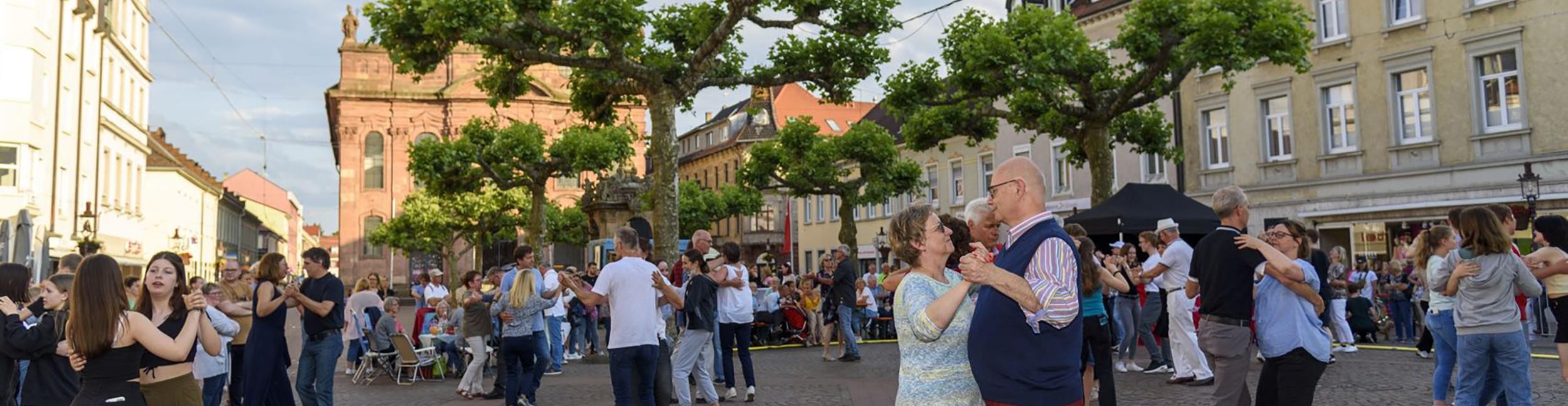 Dancing people on the market square during a dance under the plane trees
