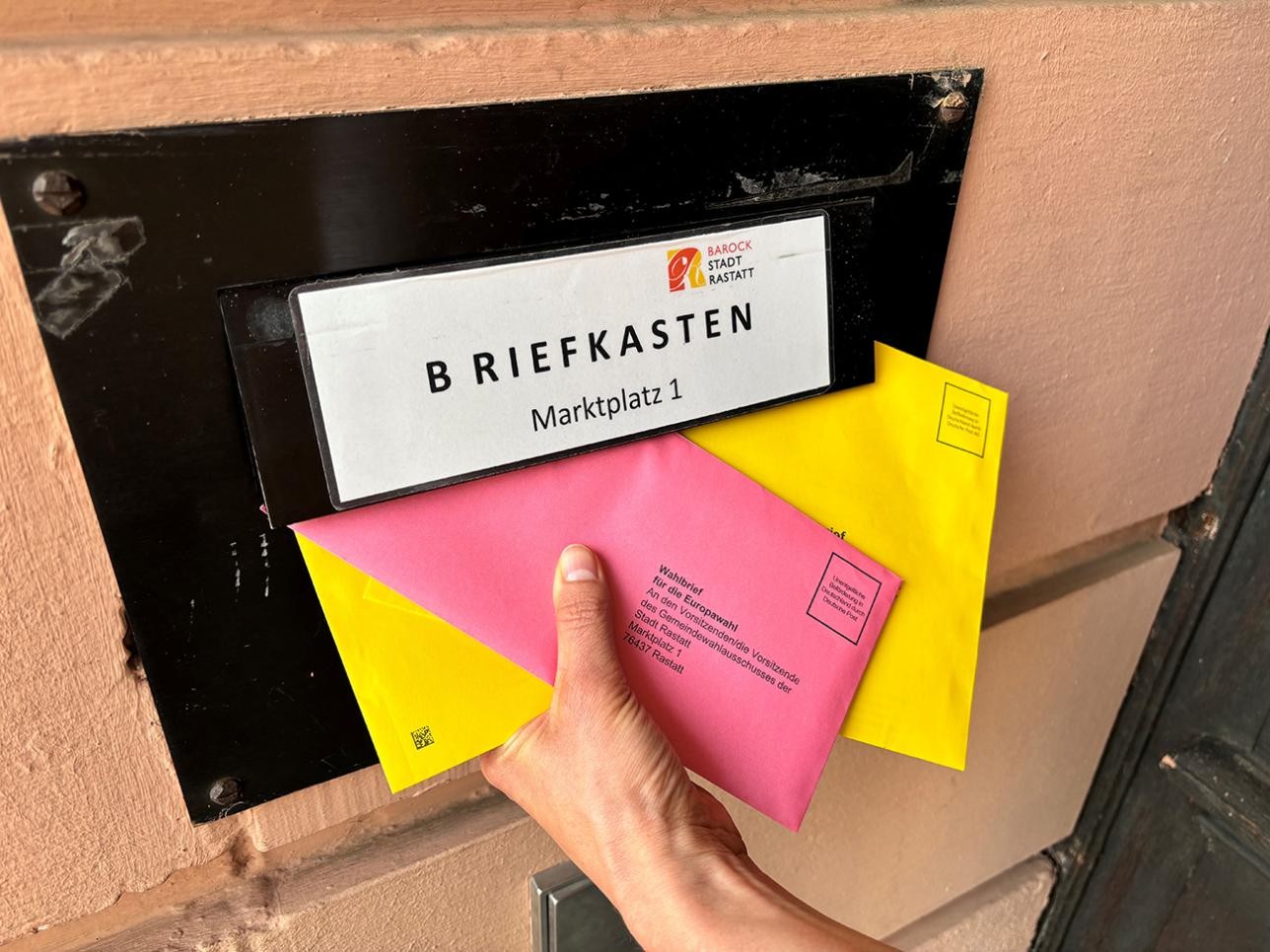 Woman throws postal voting documents into a letterbox