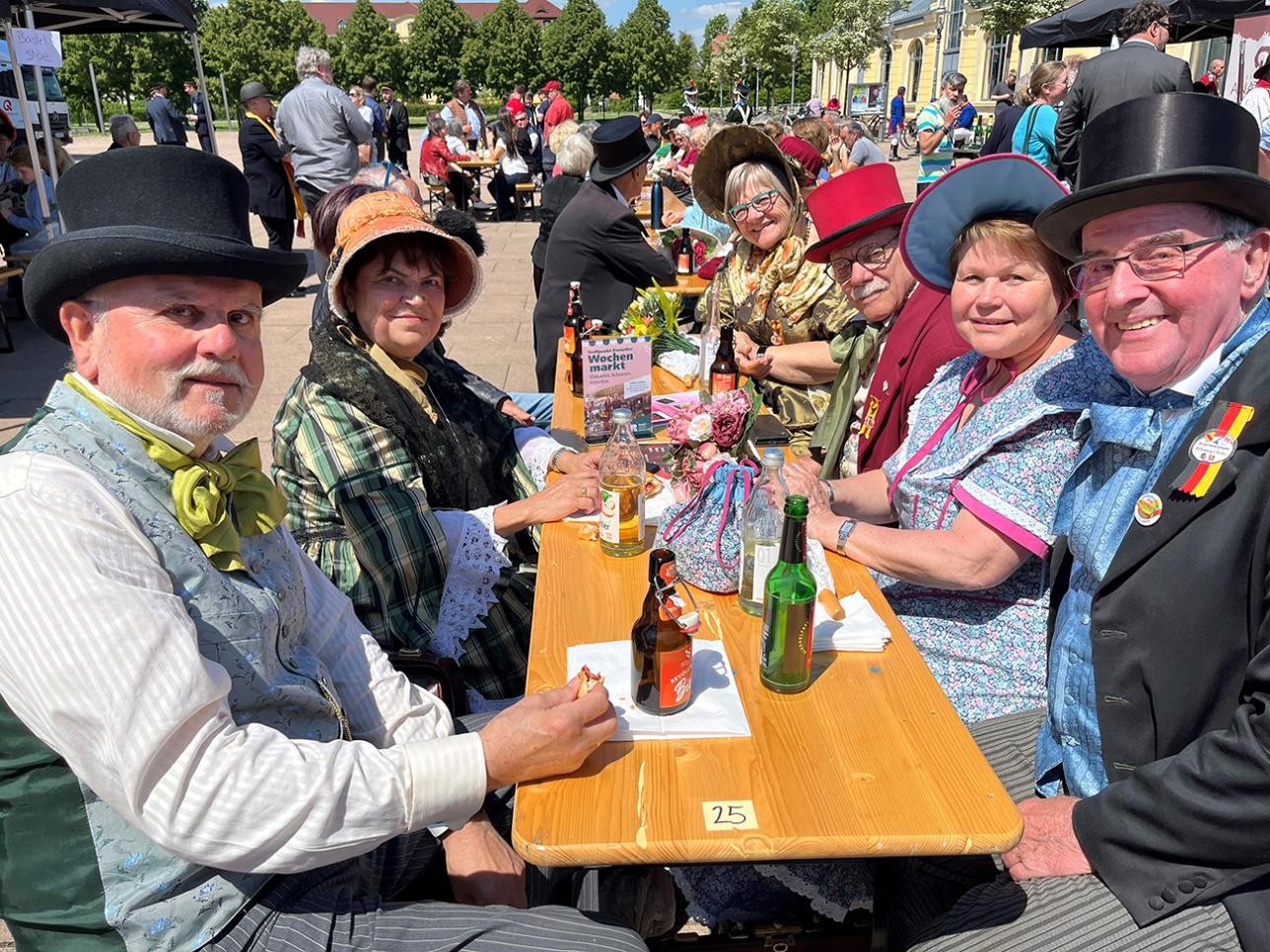 Actors sitting on a beer bench in front of the riding hall