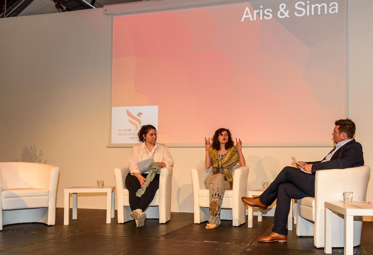 Sima Pöhler und Aris auf der Bühne mit Moderator Jochen Graf