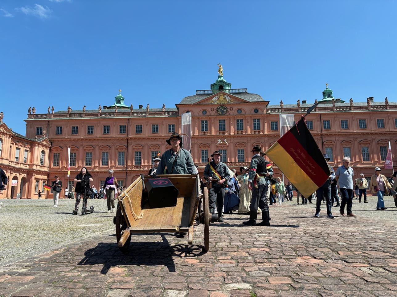 Actors run out of the courtyard towards the riding hall