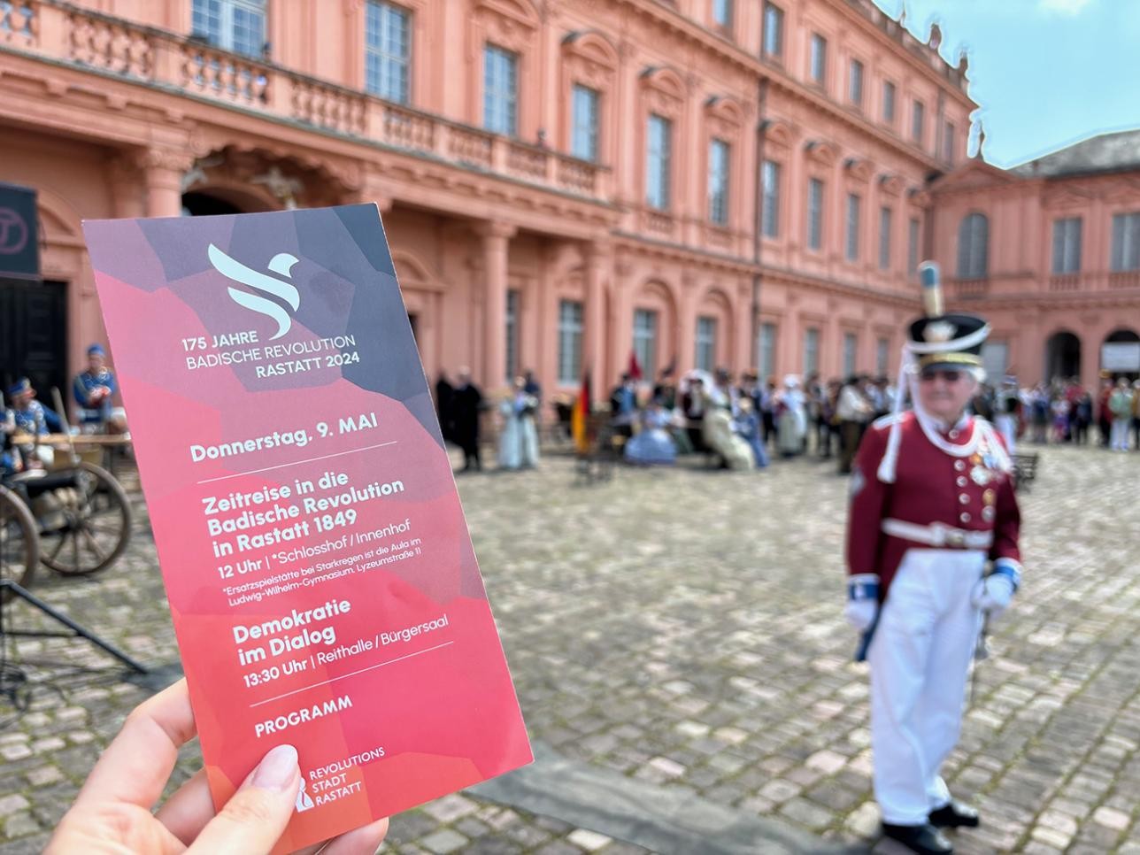 Une femme tient le programme du 9 mai en main dans la cour du château