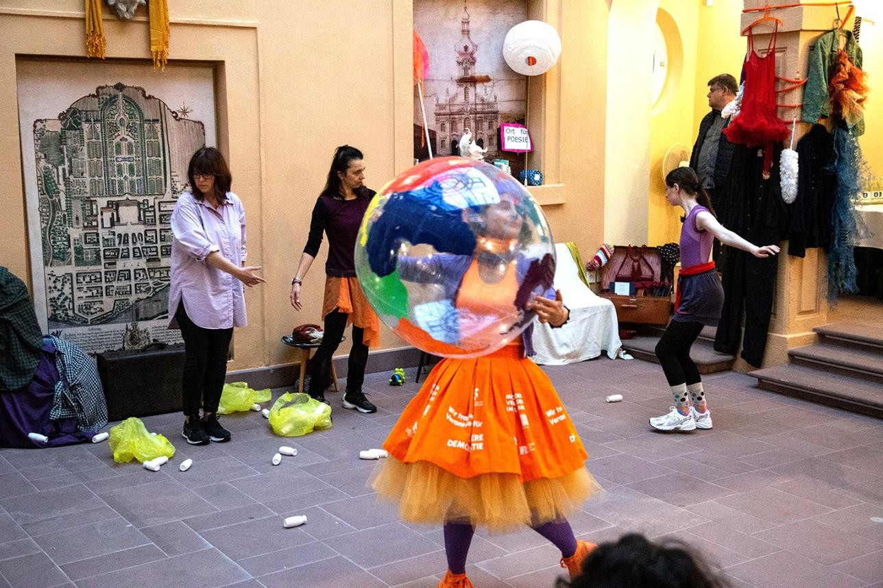 Woman dancing with large plastic ball with the earth depicted on it