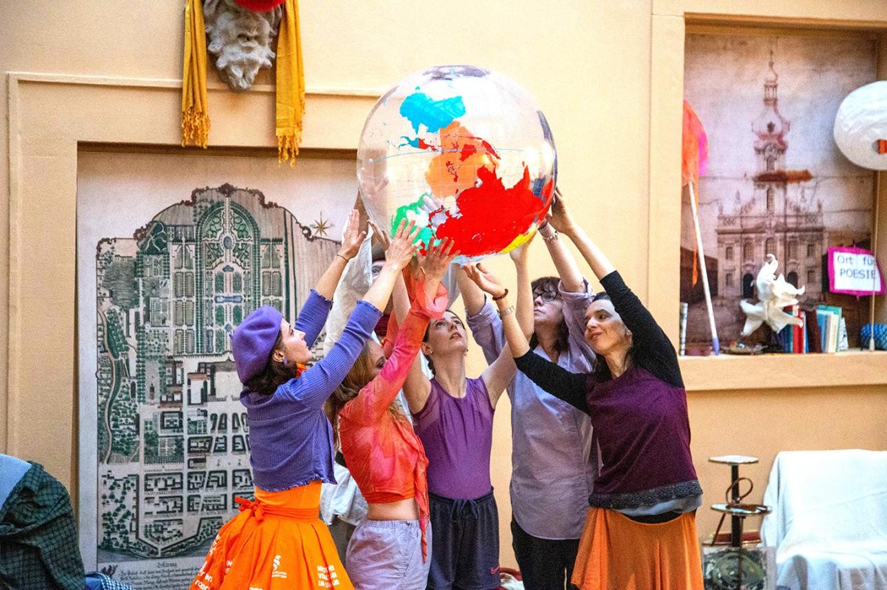 Dance group holding a large plastic ball with the earth depicted on it