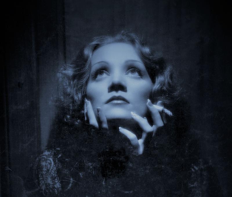 Ein schwarz-weiß Porträtfoto von Marlene Dietrich. Sie schaut nachdenklich in Richtung Zimmerdecke.