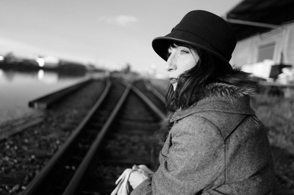 Frau steht an einem Bahnsteig und schaut in die Ferne